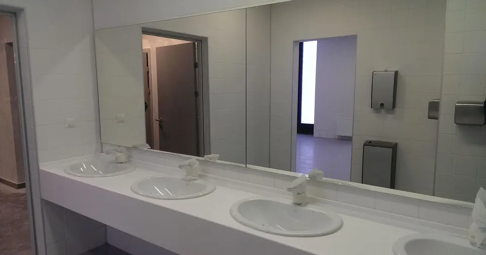 Airport washroom with a long white solid surface vanity and inset basins