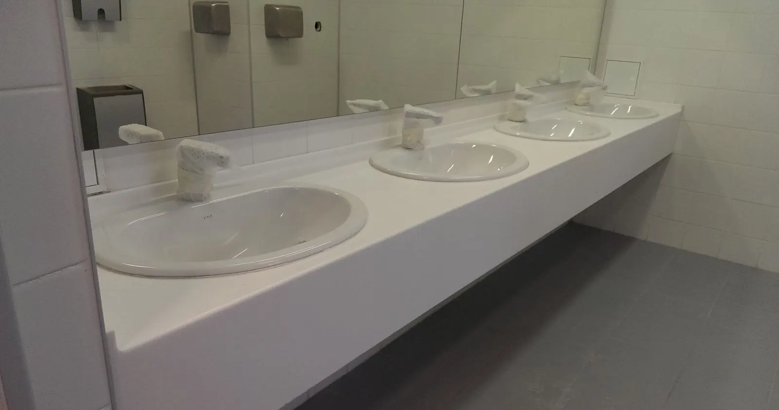 Row of inset basins in a white solid surface vanity in an airport washroom