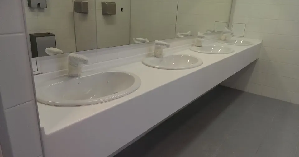 Row of inset basins in a white solid surface vanity in an airport washroom
