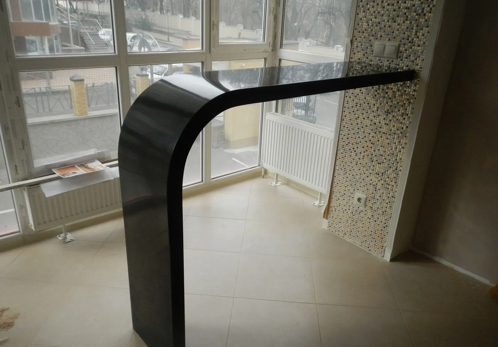 Curved black solid surface bar counter with waterfall end