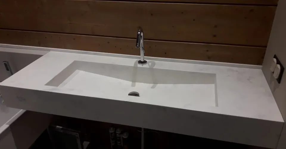 Solid surface vanity with an integrated ramp-style trough basin