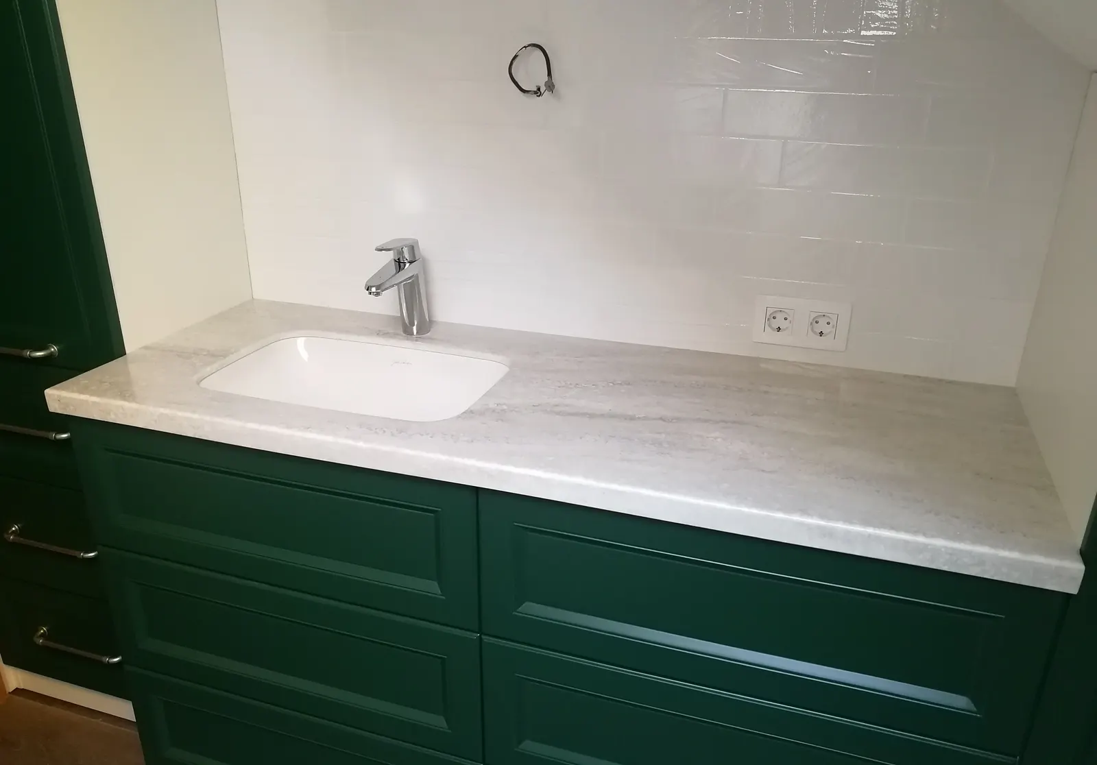 Veined solid surface vanity top with an undermount basin on a green cabinet