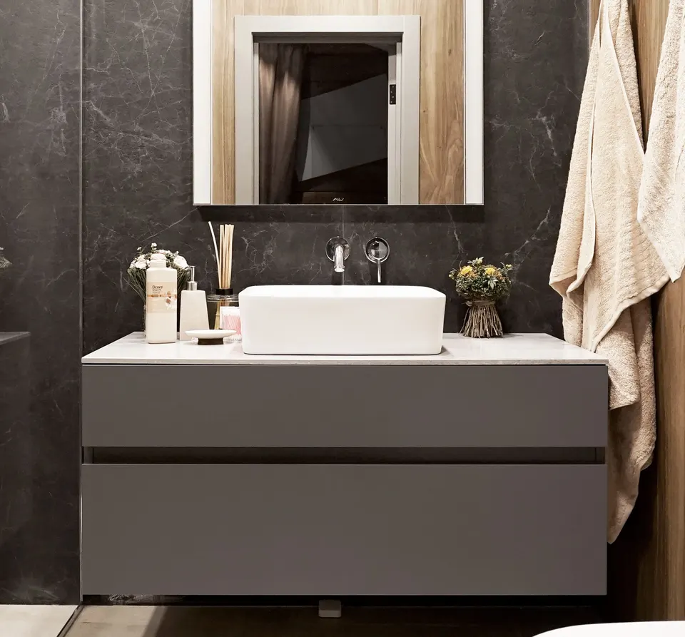 Grey solid surface vanity top with a vessel basin on a wall-hung cabinet