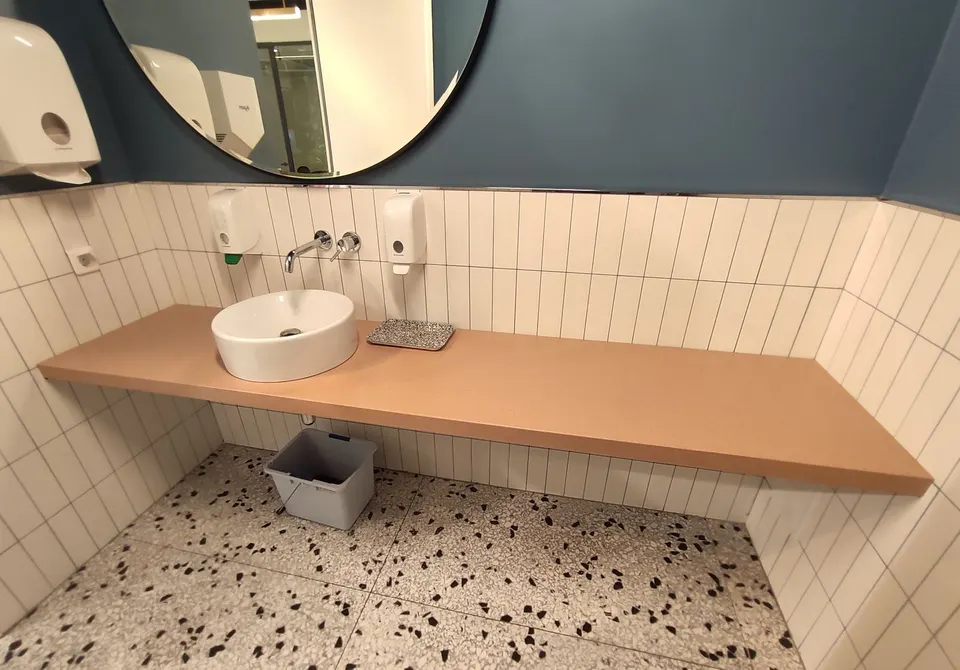 Wall-mounted Rosa Zarci solid surface vanity top with a vessel basin in a cafe washroom