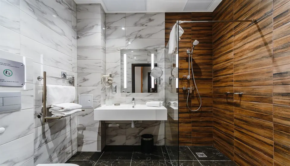 Accessible hotel bathroom with a wall-hung white solid surface washbasin and walk-in shower