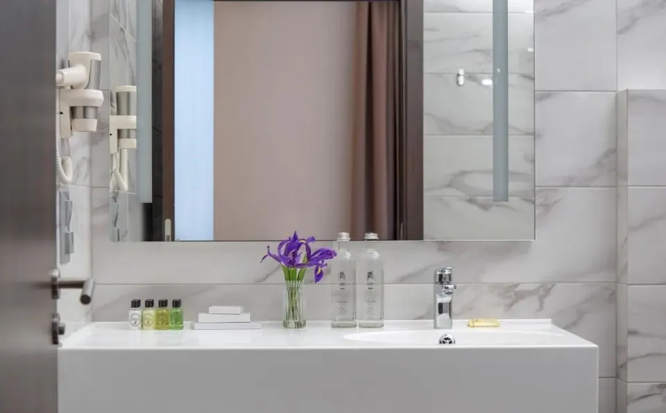 Wall-hung white solid surface vanity top with integrated basin in a hotel guest bathroom