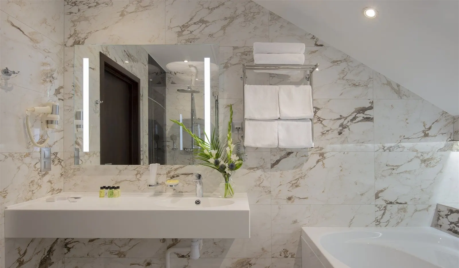 Hotel guest bathroom with a white solid surface vanity top under a sloped ceiling