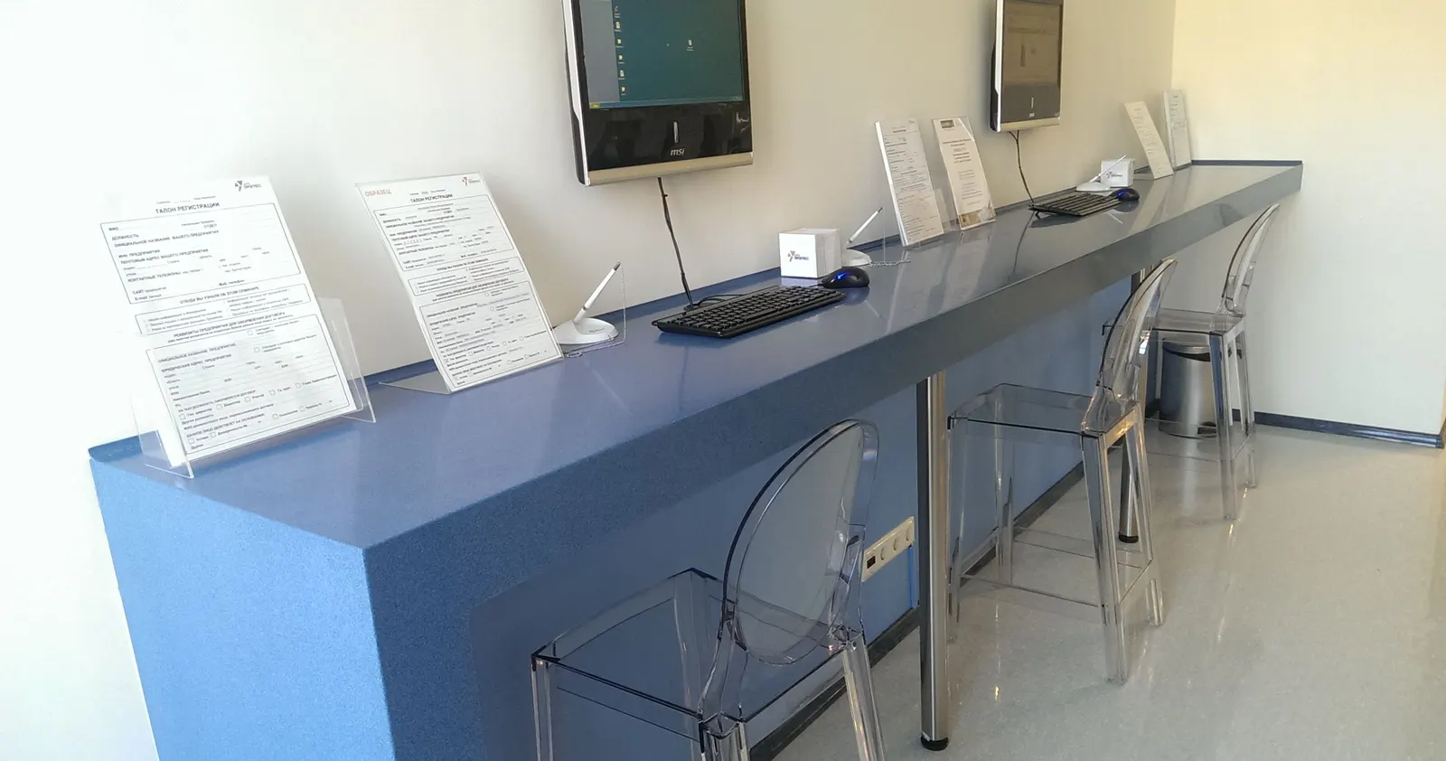 Blue solid surface standing counter with integrated desk panels in a public office