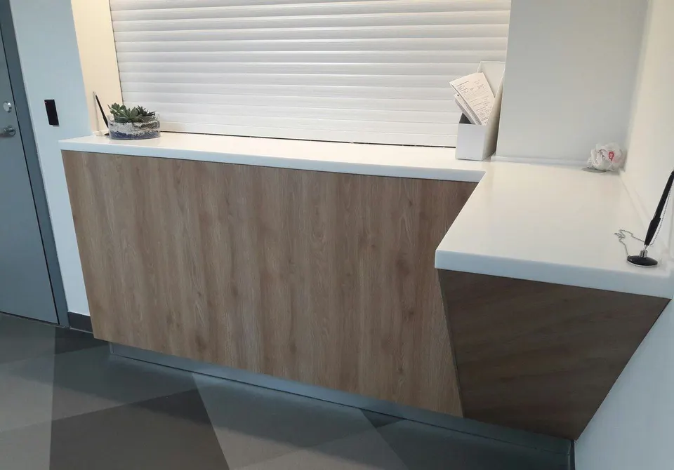 Reception counter with a white solid surface top and wood-effect front
