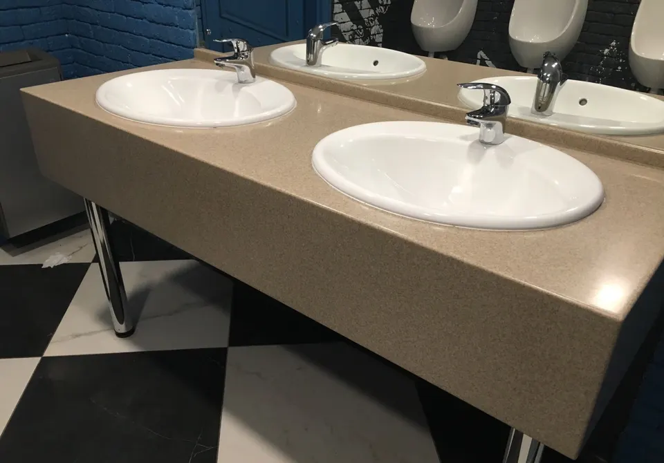 Double vanity top with inset basins on steel legs in a public washroom