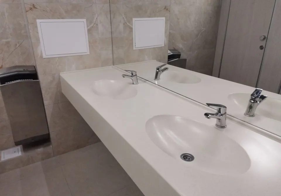 Wall-hung solid surface vanity with integrated basins in a public washroom