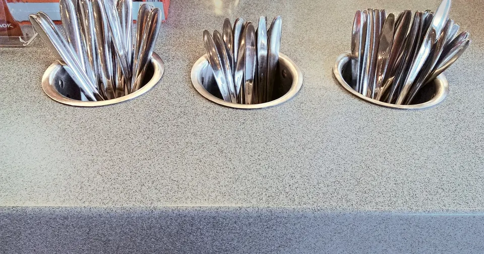Grey solid surface counter with inset cutlery holders in a quick-service restaurant