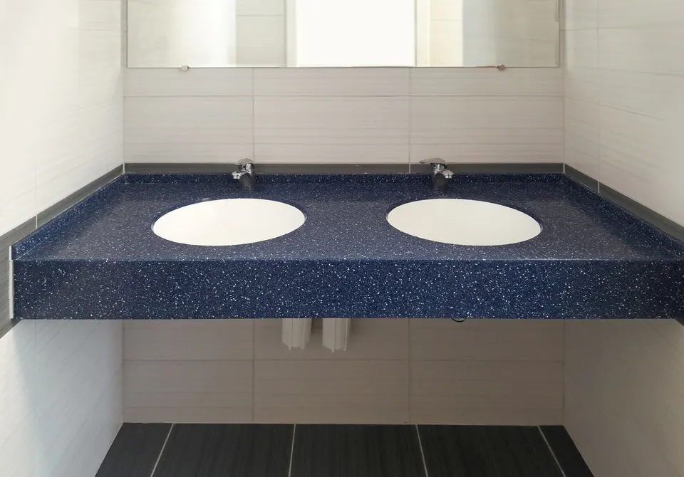 Blue speckled solid surface vanity with two undermount basins in a washroom