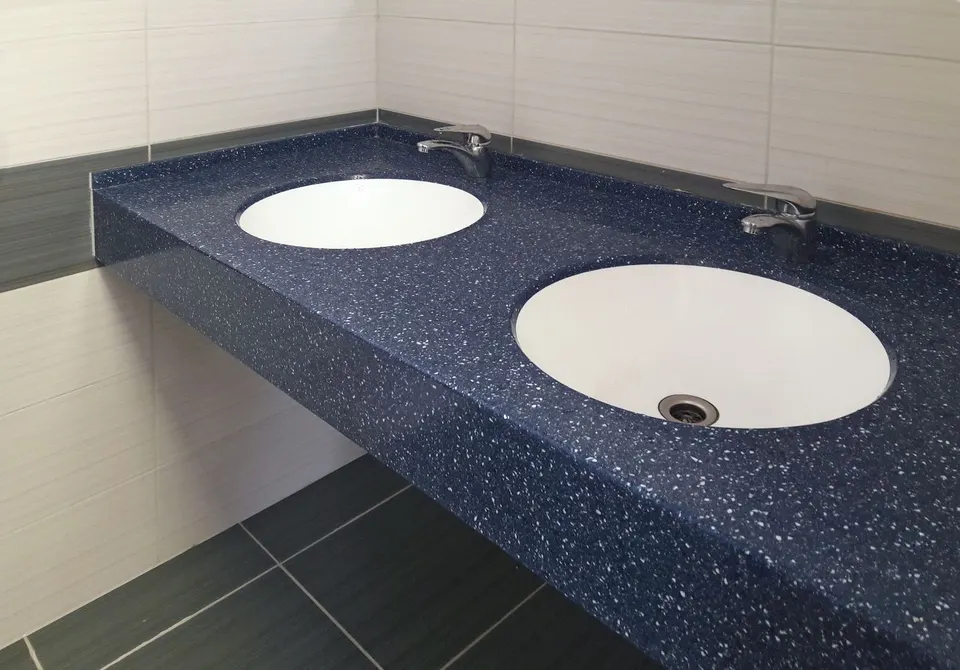 Angled view of a blue speckled solid surface washroom vanity with undermount basins